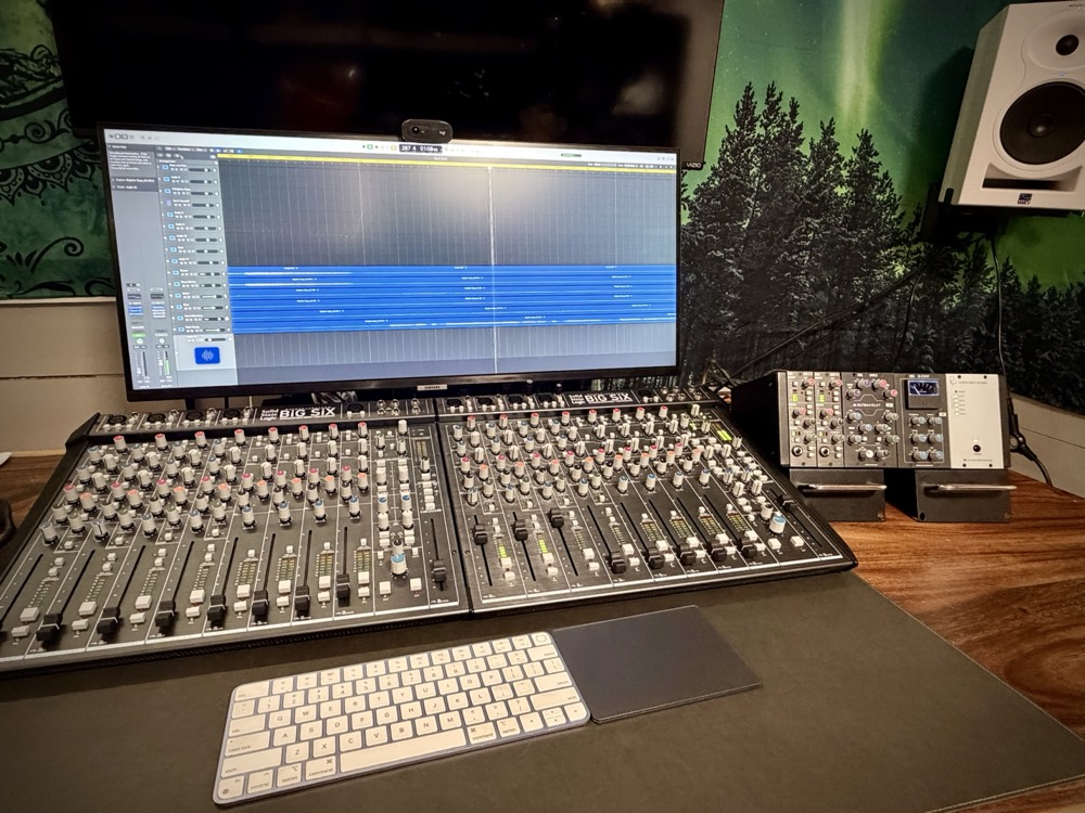 The Abeyta Audio mix position: two SSL BiG SiX consoles, a Rupert Neve Shelford channel and studio monitors in front of a pine forest mural.